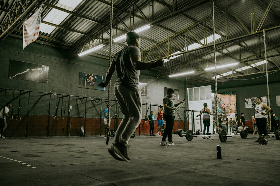 Dynamic CrossFit session with multiple adults exercising indoors using various equipment
