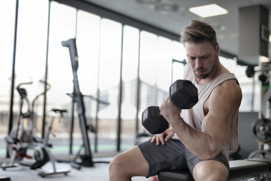 Focused man working out with a dumbbell in a well-equipped gym for strength training